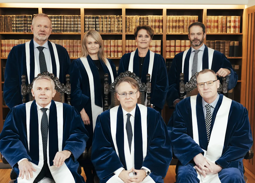 Seven people stand in two rows and pose for a photo.