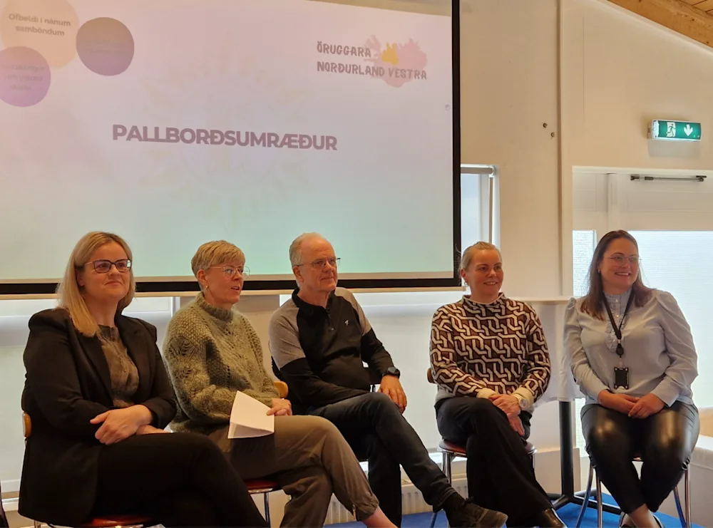 Fimm manns sitja í stólum í röð og taka þátt í pallborðsumræðum.
