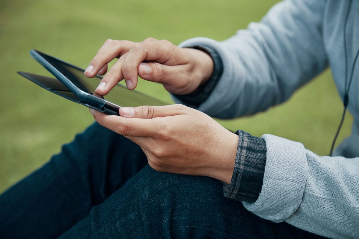 Guy browsing tablet in park