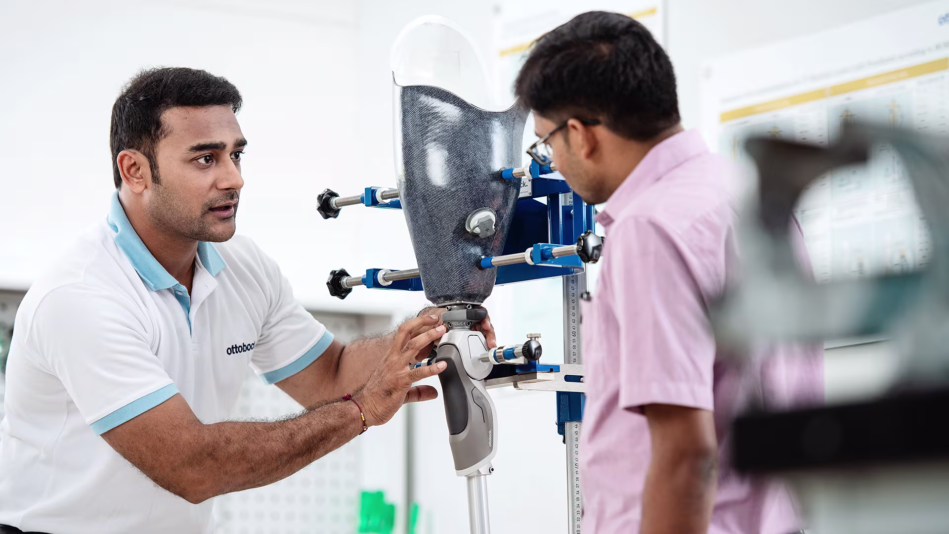 A male amputee veteran sits in a clinic with his prosthetist and extends his leg for a 3D scan.