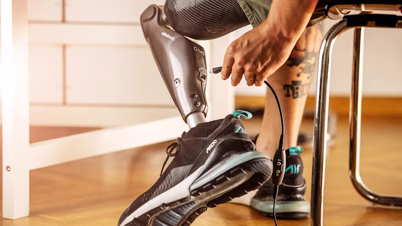Un uomo inserisce un cavo di ricarica nella parte posteriore del suo C-Leg 4 con una sola mano
