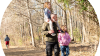 A family of three walking on an outdoor trail. The father holds his daughter on his shoulders without strain thanks to his custom-made Ottobock C-Brace