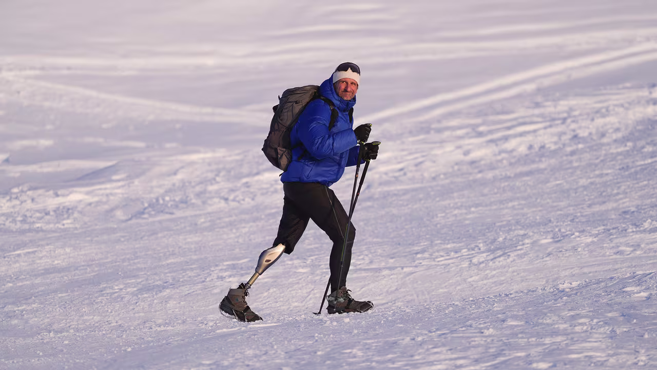 Ein Prothesenträger wandert auf einem Berg mit viel Schnee. Er trägt das mechatronische Prothesenkniegelenk Genium X4 von Ottobock.