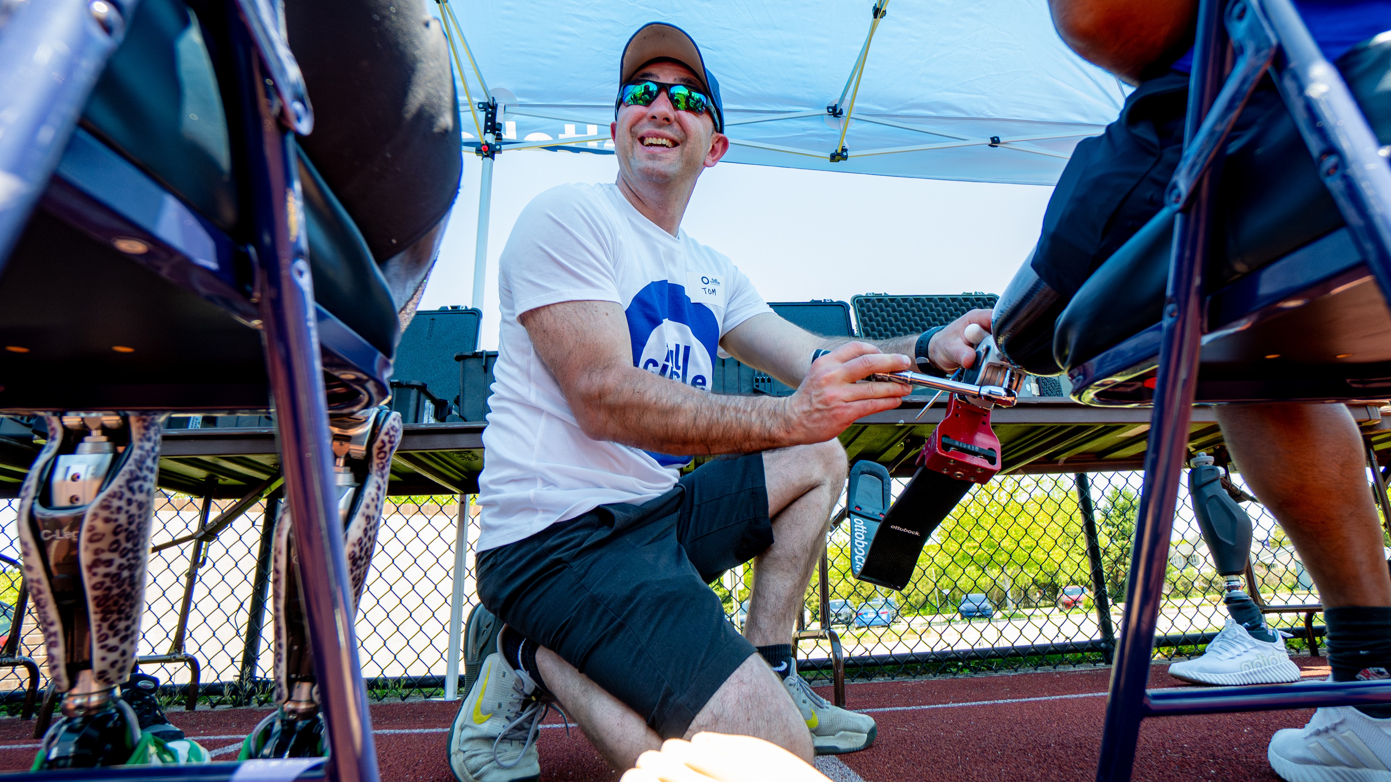 A volunteer clinician adjusts a running prosthetic on a Full Circle Movement participant