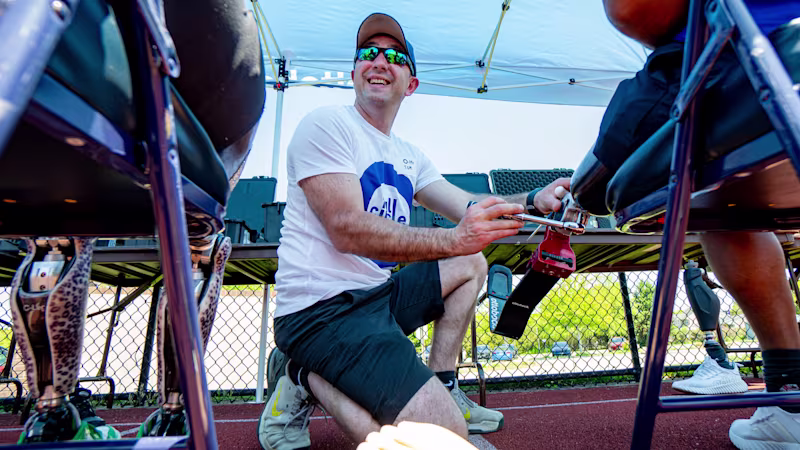 A volunteer clinician adjusts a running prosthetic on a Full Circle Movement participant