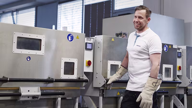 Smiling Ottobock fabrication employee standing in an O&P workshop in front of an oven.