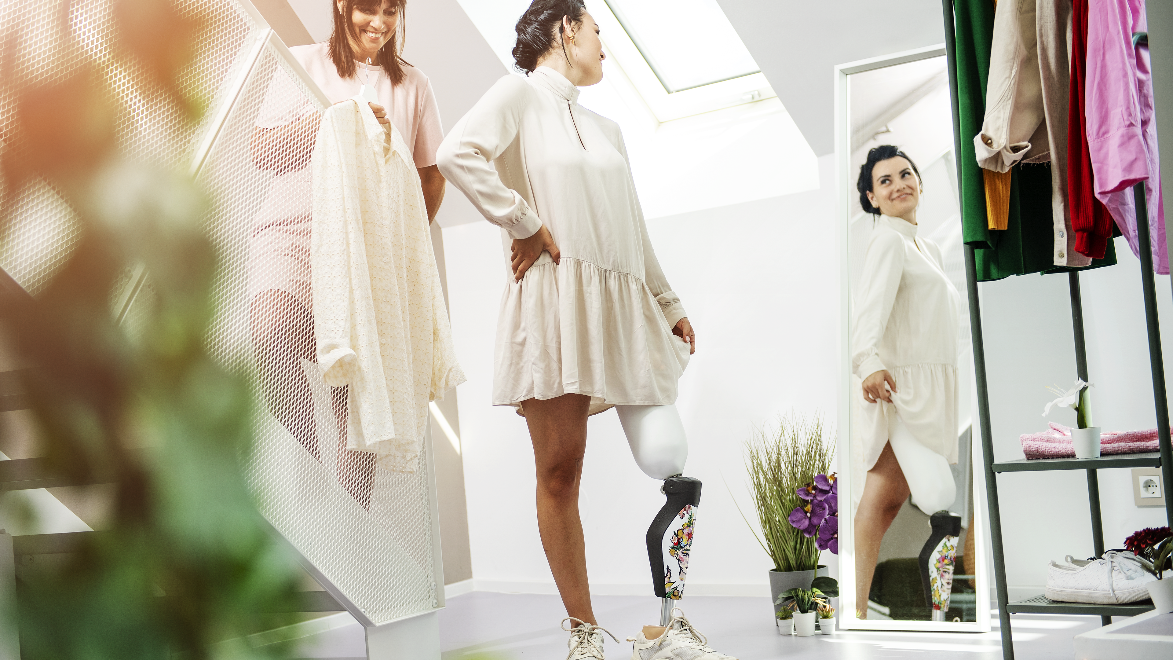 A young Ottobock C-Leg 4 user trying on clothes in front of a mirror together with her mother. 