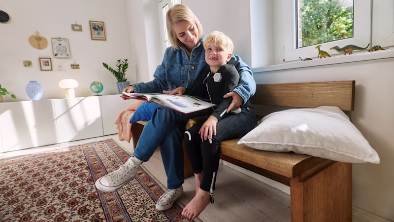 Child wearing the exopulse suit for children while reading at home