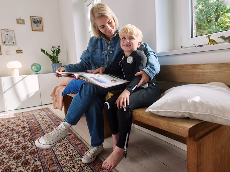 Child wearing the exopulse suit for children while reading at home