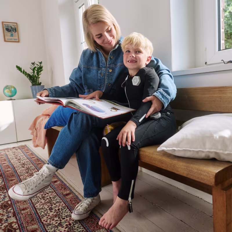Child wearing the exopulse suit for children while reading at home