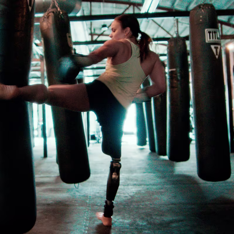 Amy stands on her C-Leg 4 as she kicks a heavy bag with her other leg