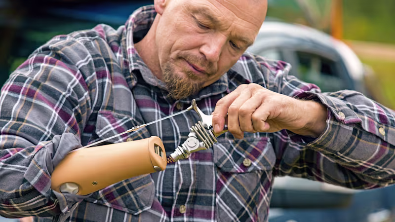 User operating mechanical tool with advanced prosthetic arm in workshop setting.