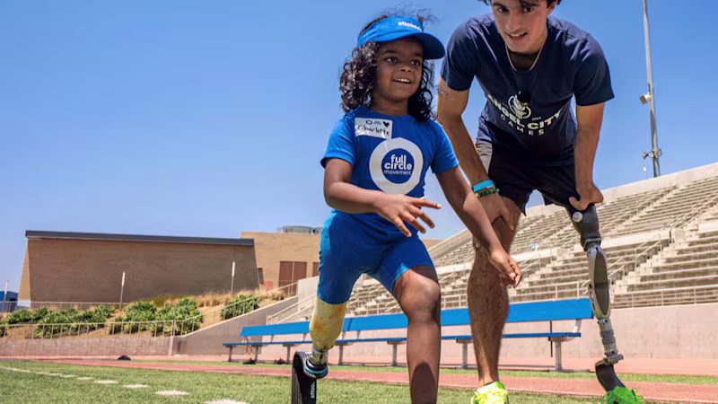 Paralympian with prosthetic leg coaching young girl who also has a prosthetic leg how to run