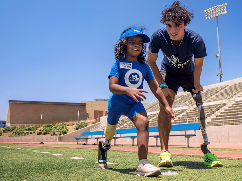 Paralympian with prosthetic leg coaching young girl who also has a prosthetic leg how to run