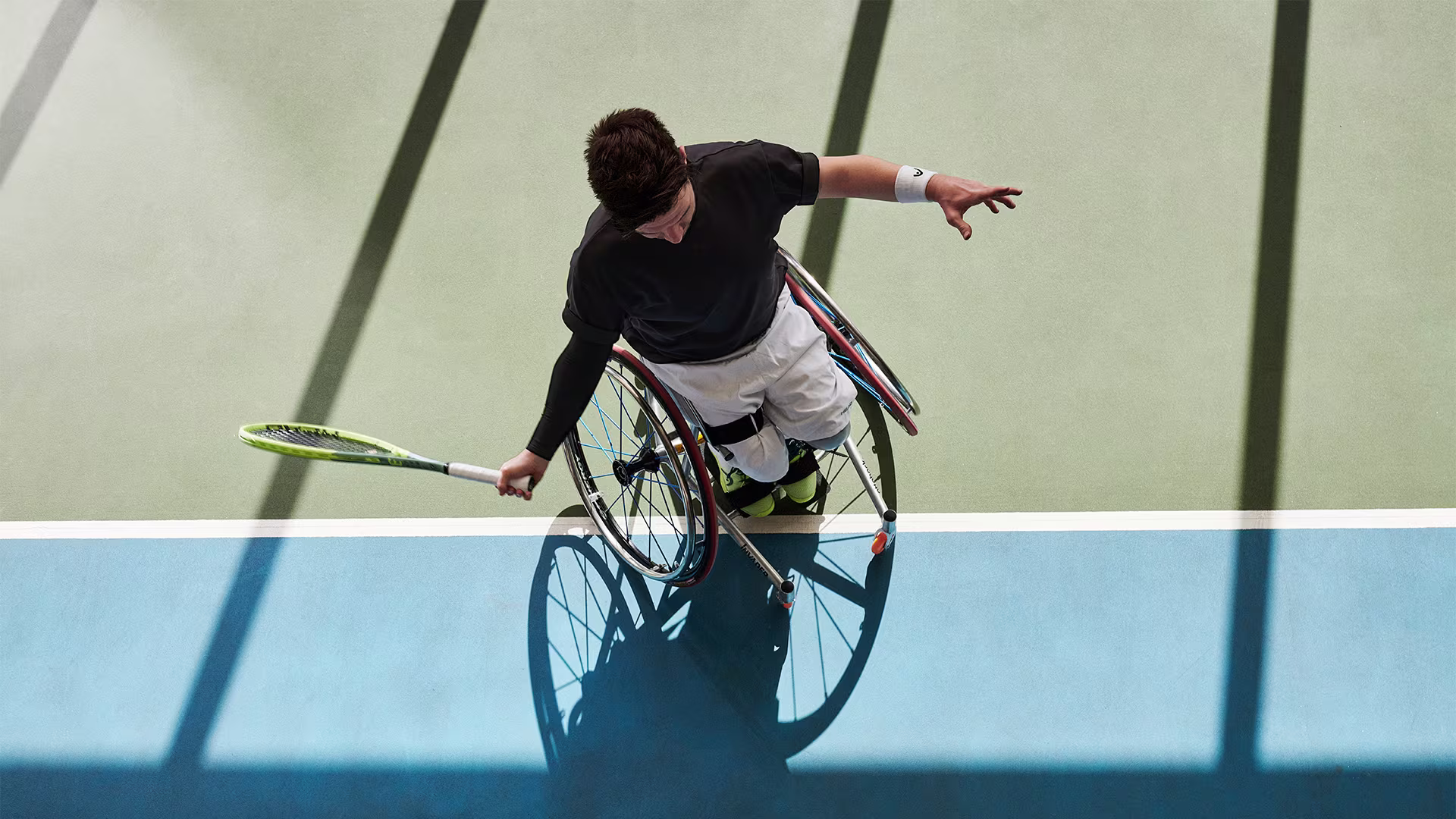 Overhead view of a wheelchair tennis pro swinging his racket on the tennis court