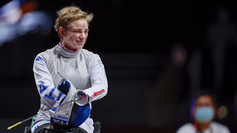 Paralympic fencer Beatrice Vio takes off her fencing mask and smiles in her fencing sports wheelchair