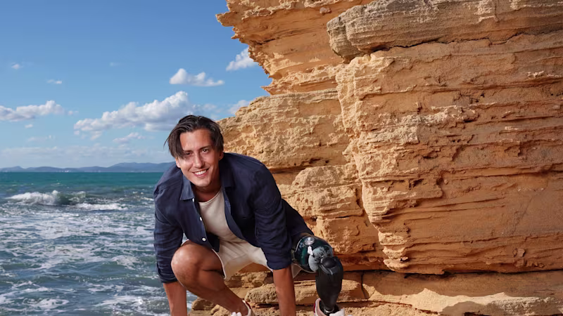 A male user squats against a rock with his Ottobock Evanto prosthetic foot.