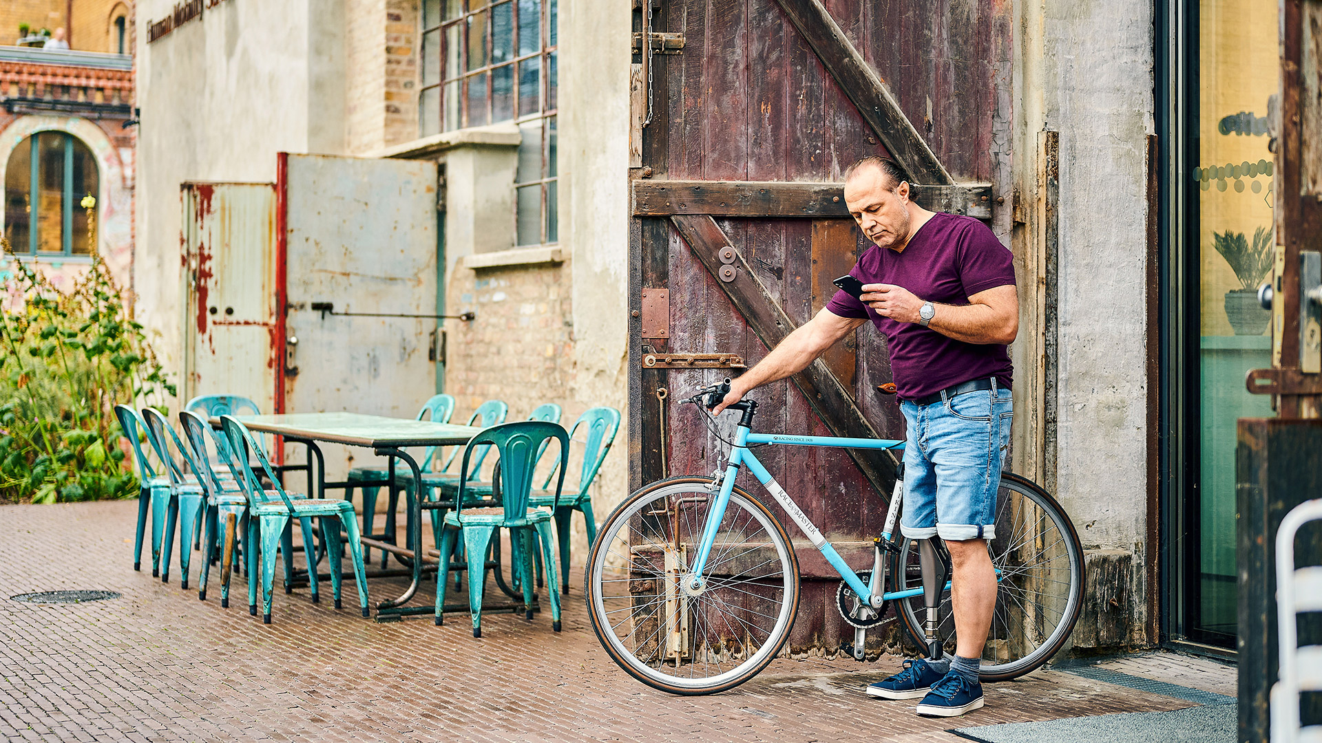An amputee leaning against a wall, drinking his juice and wearing his Ottobock C-Leg 4.