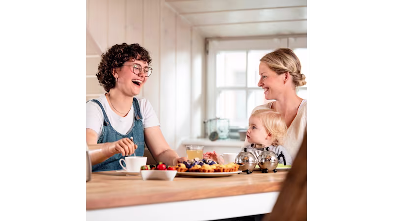 Ragazza con gli occhiali facendo uso di una mano protesica Ottobock a colazione con la famiglia.