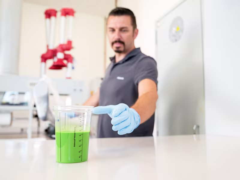 Man in an O&P Workshop reaching out to a cup of Ottobock OrthoEpox Greenline in front of him