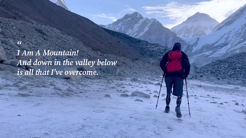 Bilateral amputee wearing Ottobock Genium X3 microprocessor knees hiking in front of mountains.