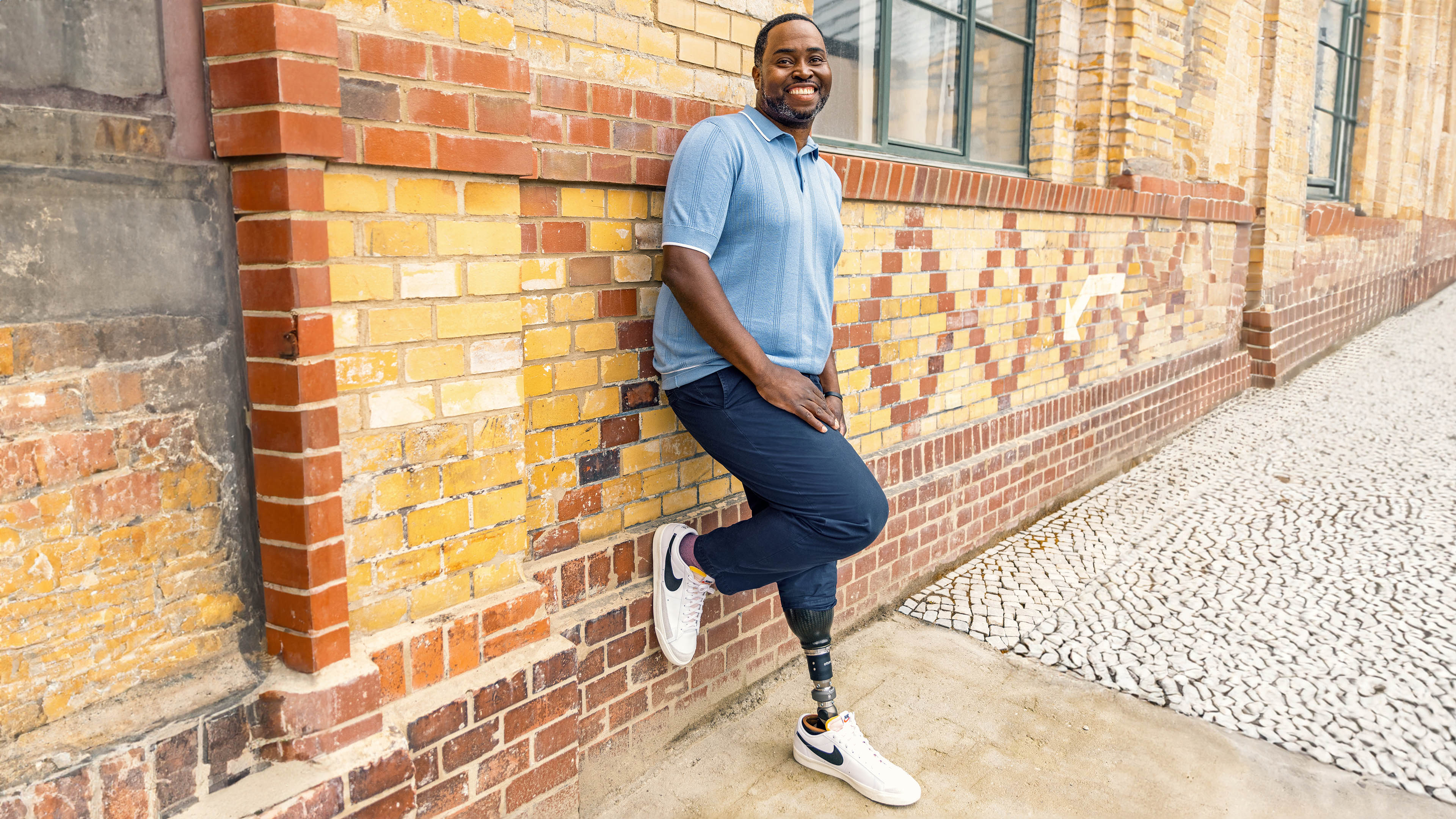 Prosthetic foot user, Carlos, leaning against a brick wall with his Taleo Adapt