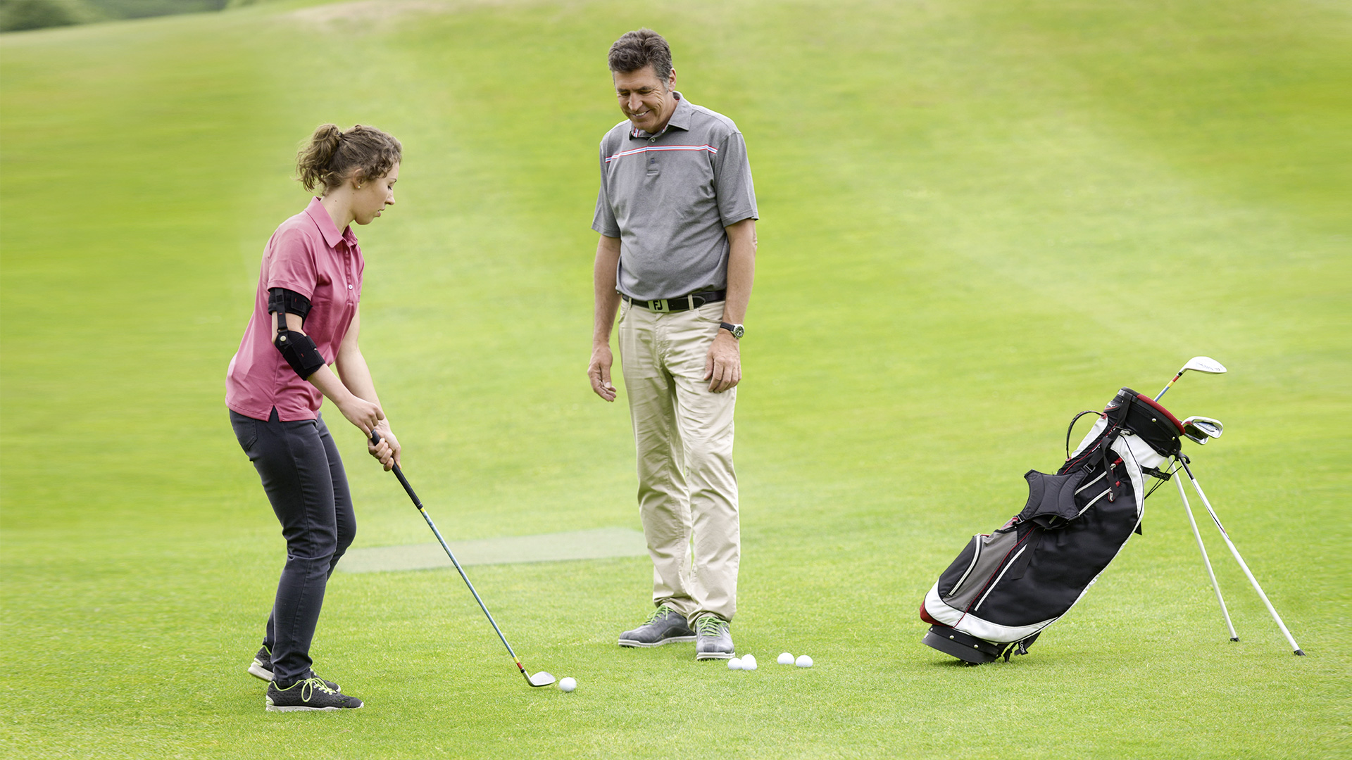A couple plays golf outside. The woman is preparing to take her shot while wearing a custom Ottobock Omo Neurexa plus