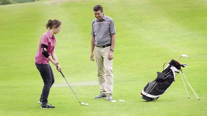 A couple plays golf outside. The woman is preparing to take her shot while wearing a custom Ottobock Omo Neurexa plus