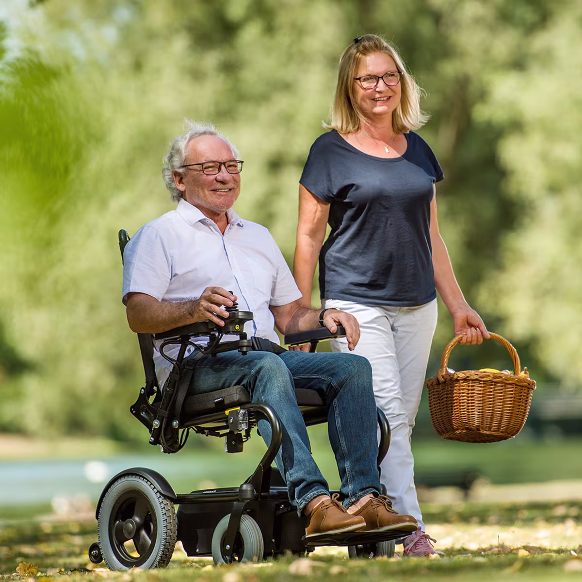 A male person drives through a green park with his Wingus power wheelchair.