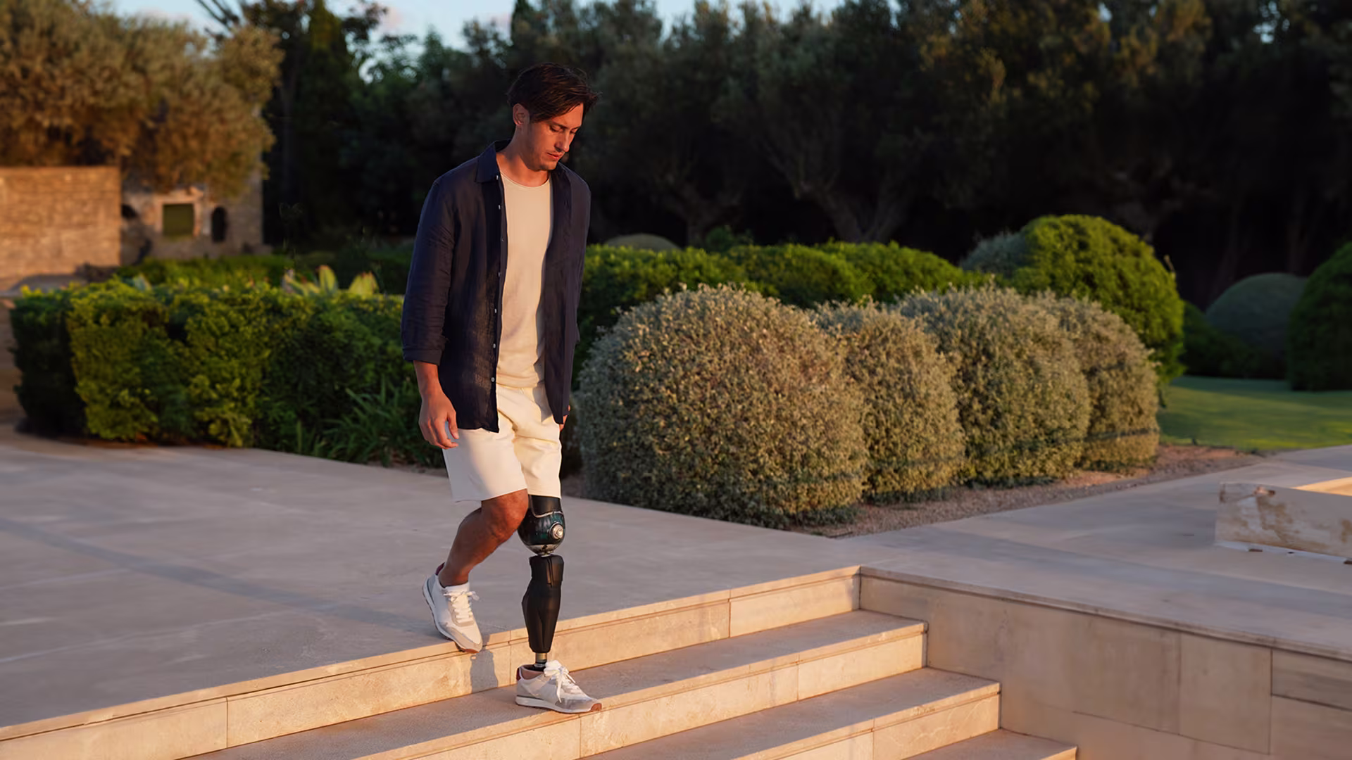 A man wearing the Trias carbon prosthetic foot by Ottobock while walking down a set of stairs