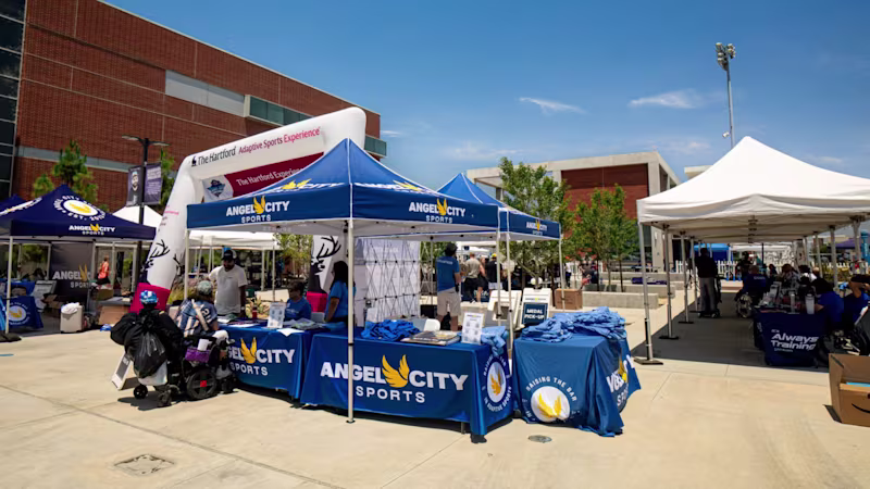 A sunny outdoor venue with event tents with a main Angel City Sports tent in the foreground