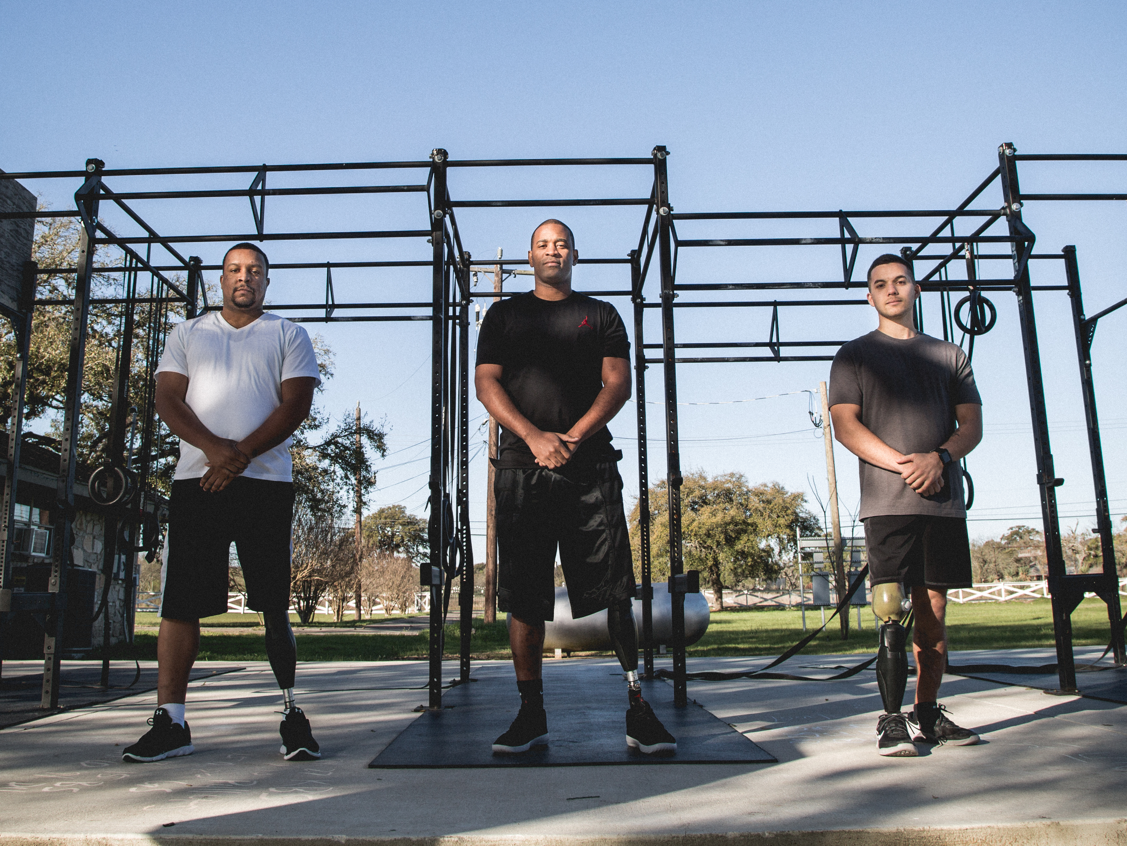 Three United States veterans in Ottobock leg prosthetics standing in front of an outdoor gym