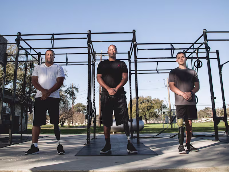 Three United States veterans in Ottobock leg prosthetics standing in front of an outdoor gym