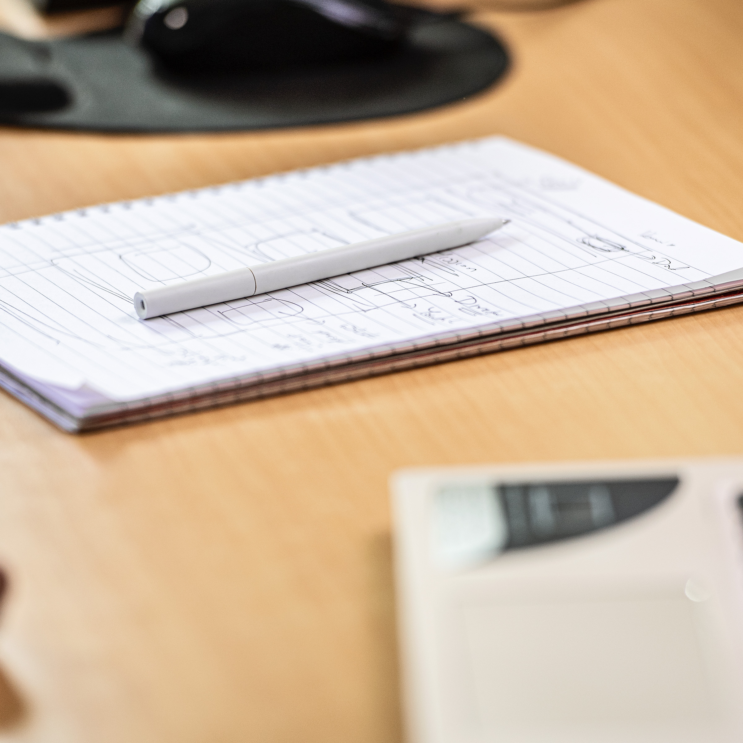 Pen and notebook placed on a desk in a working environment.