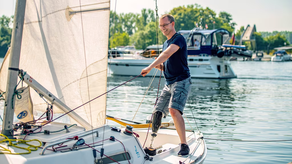 A male user is standing on a sailing boat with his Taleo Side Flex foot.