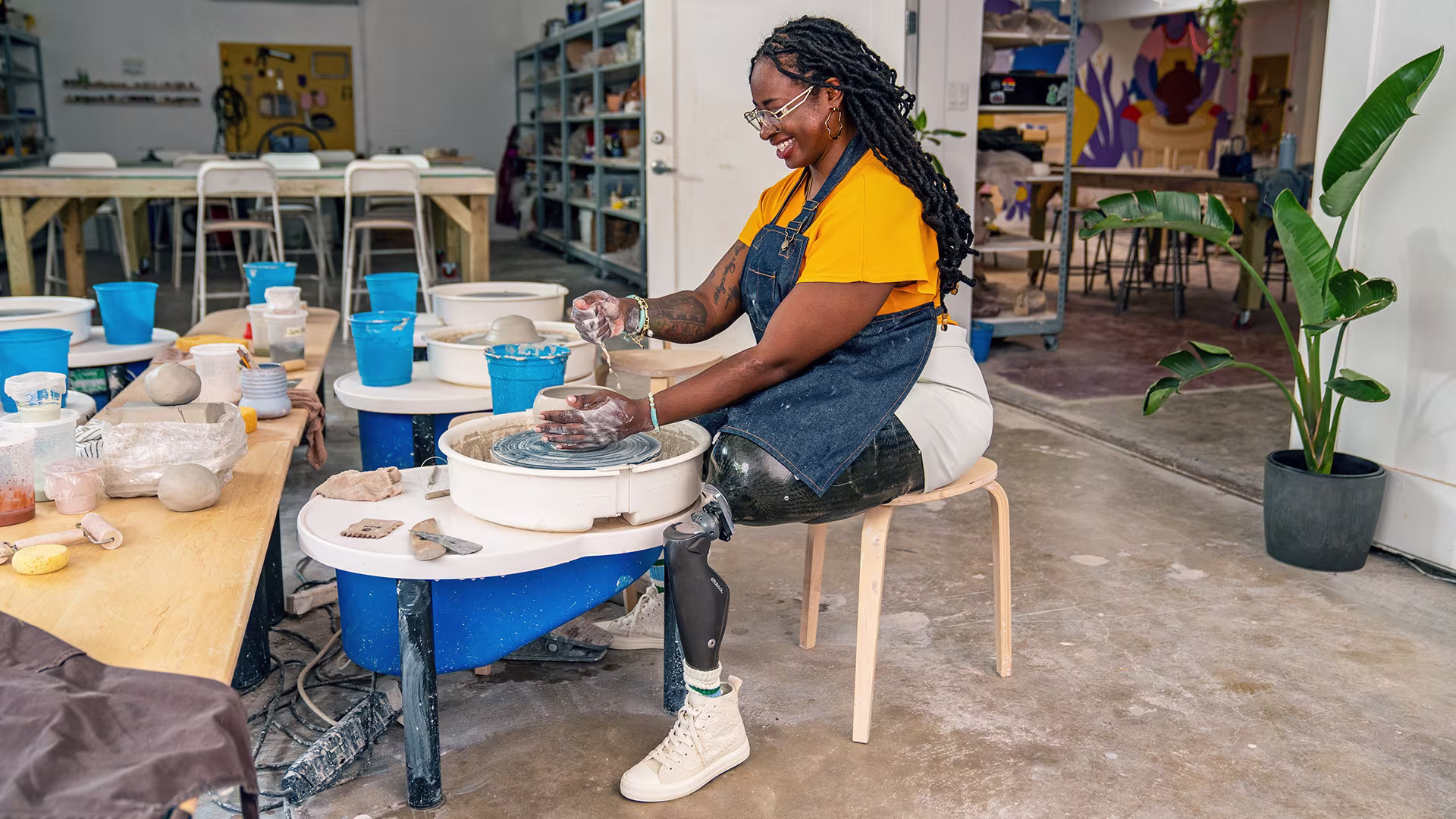 Shima, a C-Leg prosthetic user, modeling a figure out of clay.