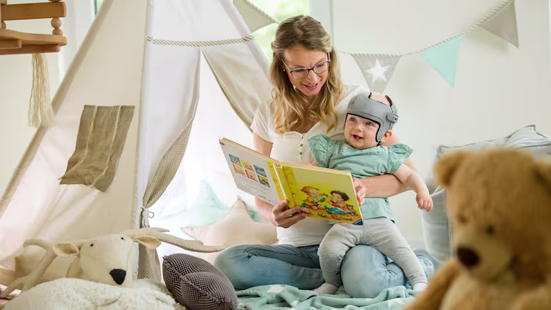A mother reading a children's book to their child whose wearing the MyCRO Band