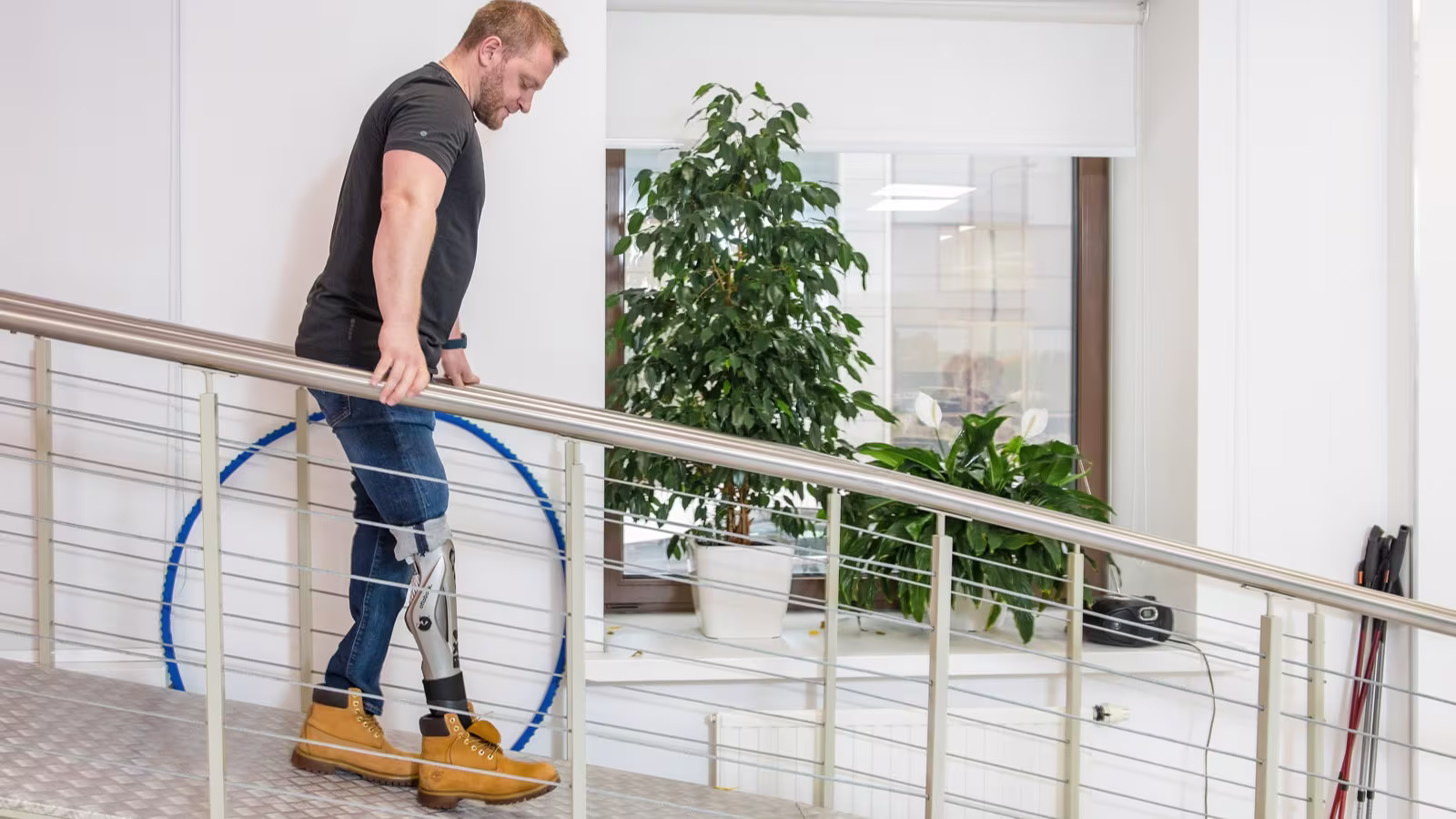 Мужчина на протезе спускается по пандусу в протезной мастерской Ottobock.