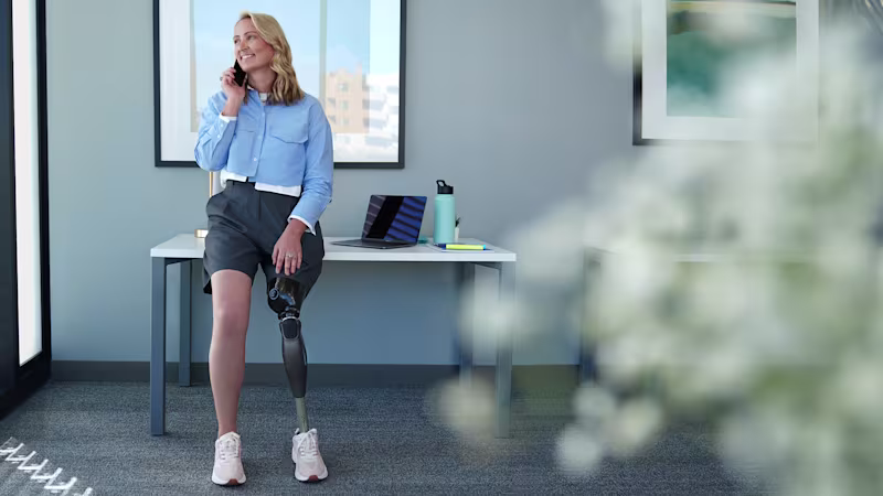 A woman standing in her office while talking on her phone and wearing her Ottobock Genium X4.