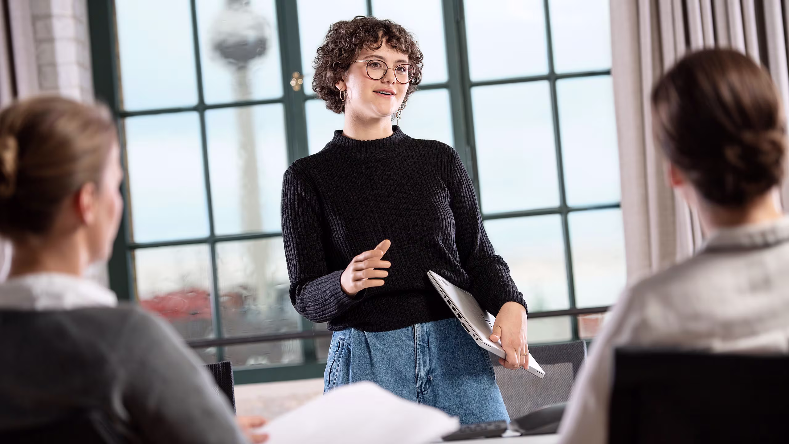 Utente ottobock con una mano protesica che presenta di fronte a due persone, la torre della televisione di Berlino sullo sfondo.