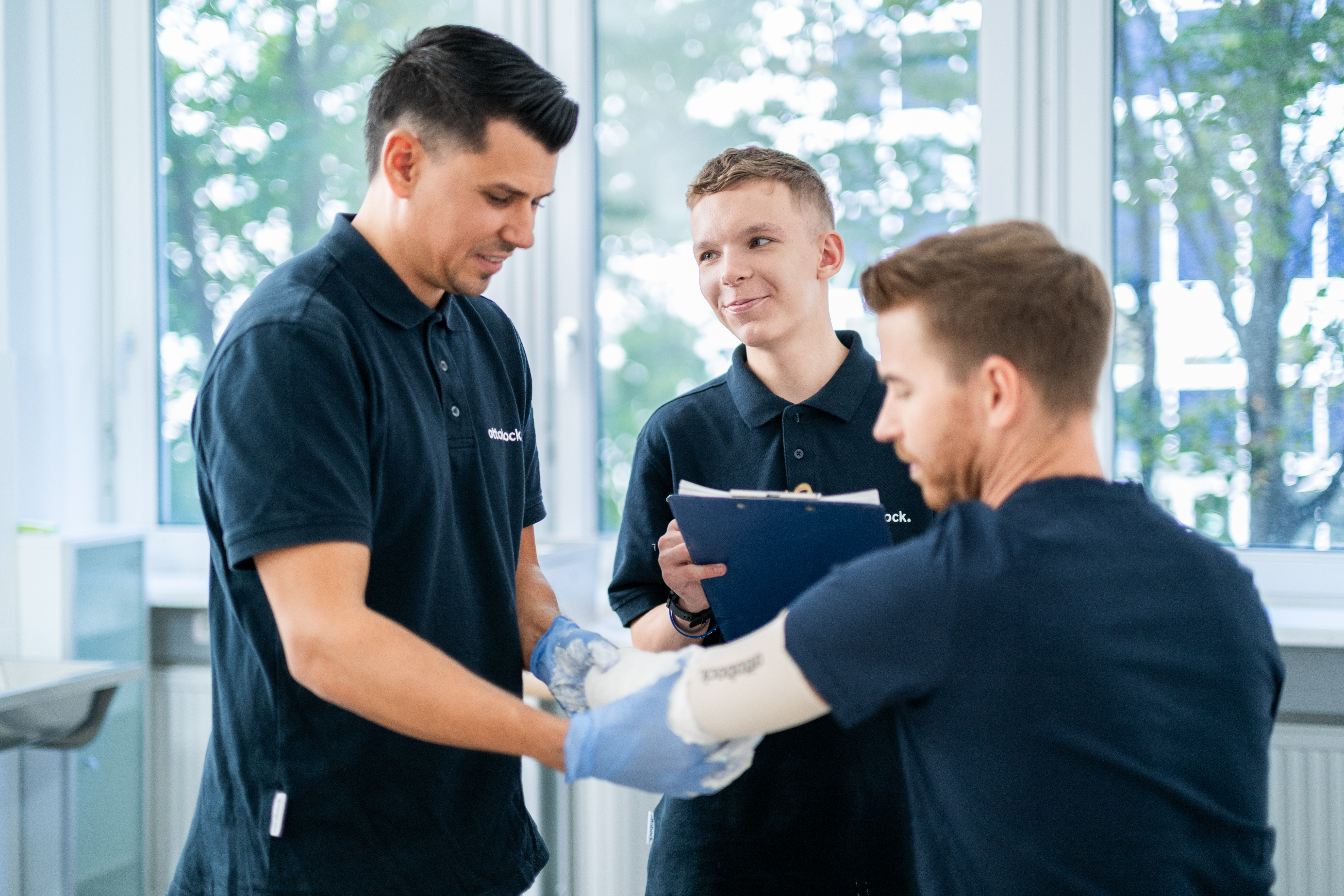 Auf dem Bild sieht man einen Ausbilder und einen Lehrling. Der Ausbilder macht gerade einen Abdruck von dem Armstumpf eines Anwenders.