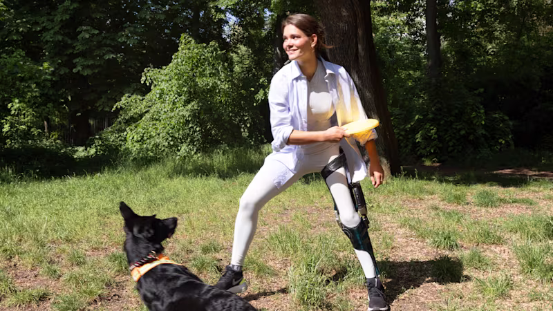 Eine weibliche Anwenderin spielt mit ihrem Hund Frisbee, dabei trägt Sie die Beinorthesen C-Brace von Ottobock.