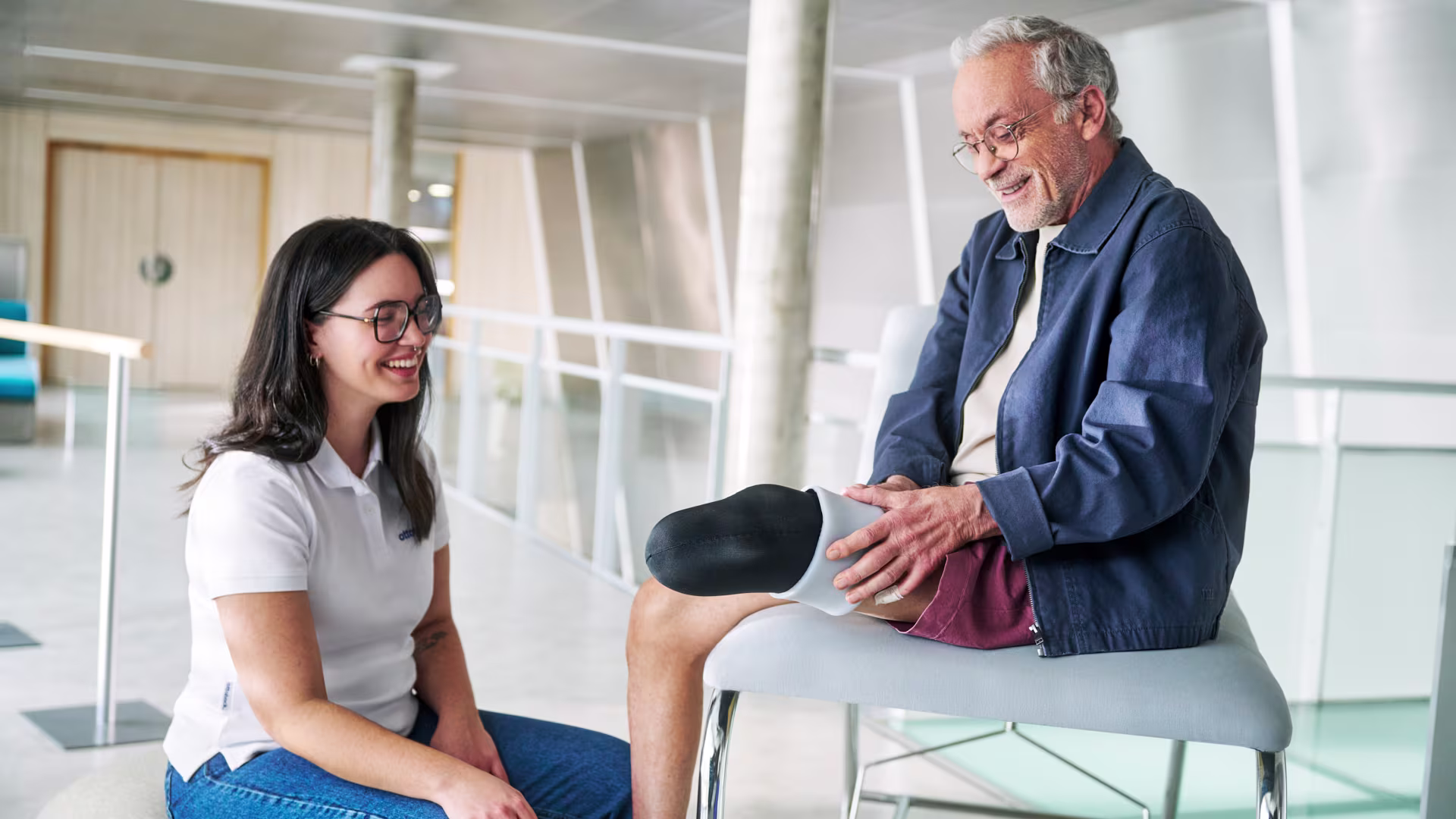 A male patient is sitting on a chair and trying a black Ottobock liner