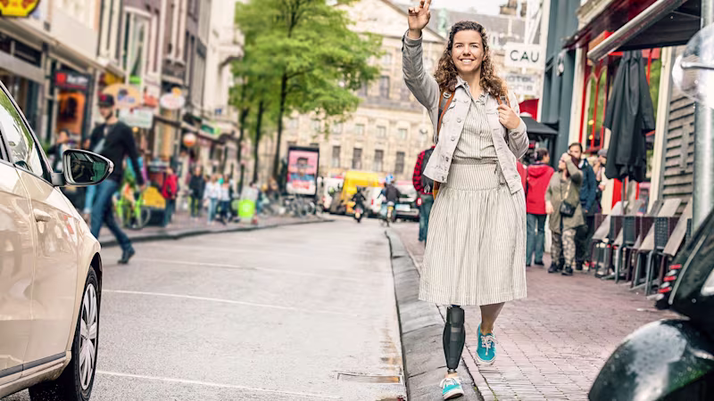 Genium X3 user Marije waves to a friend as she stands on a slanted road