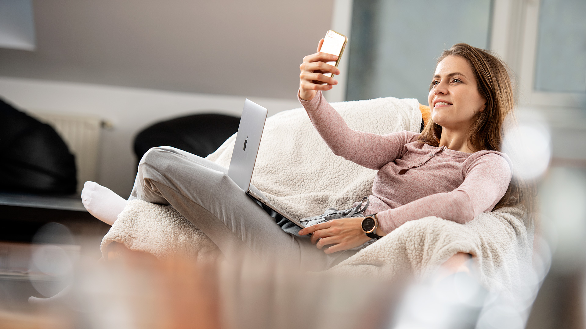 Réka mit Smartphone auf dem Sofa