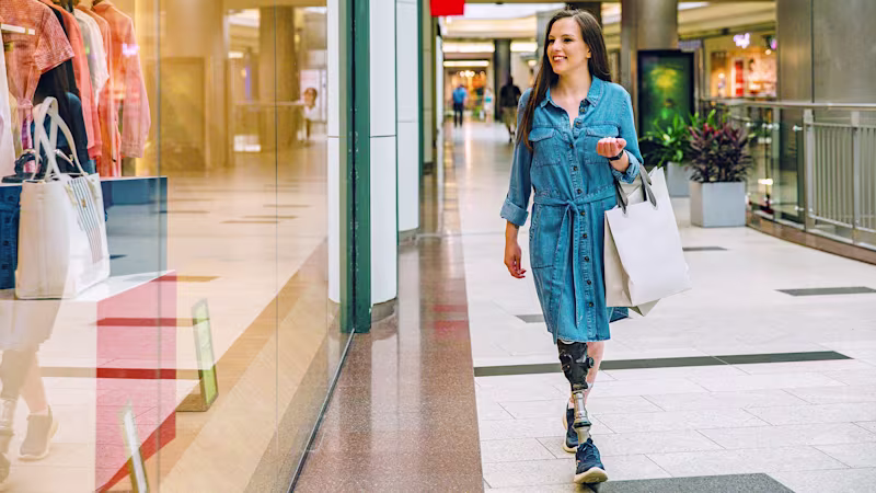 A female user is wearing shopping bags while walking with her Taleo Vertical Shock foot.