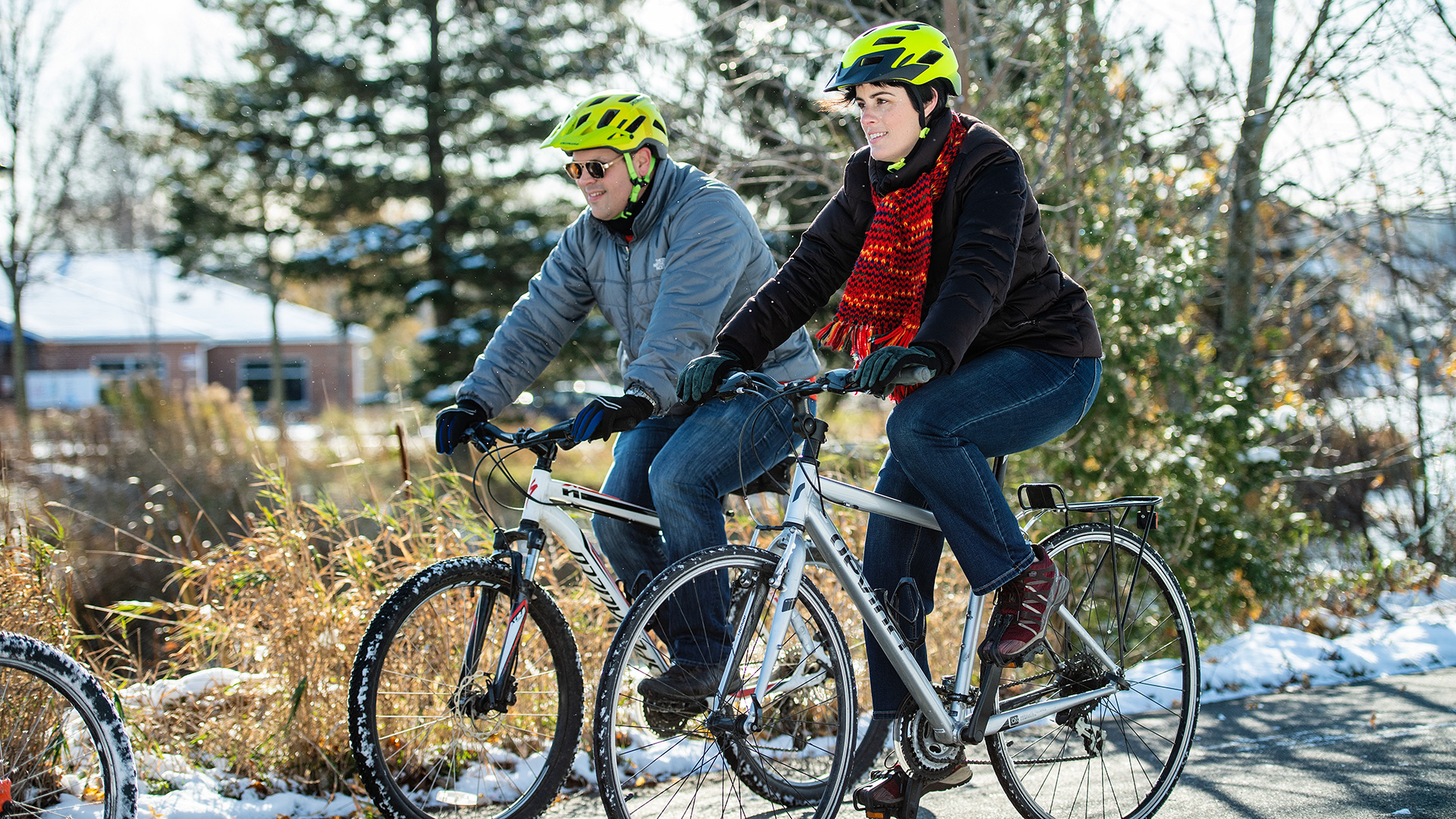 Amputee rides a bicycle outdoors with a companion