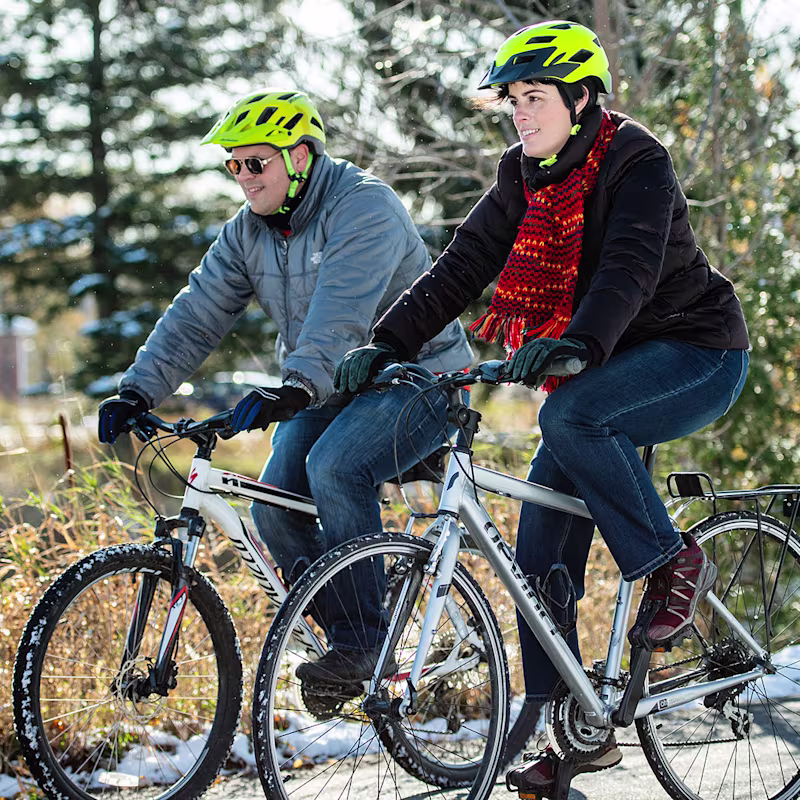 Amputee rides a bicycle outdoors with a companion