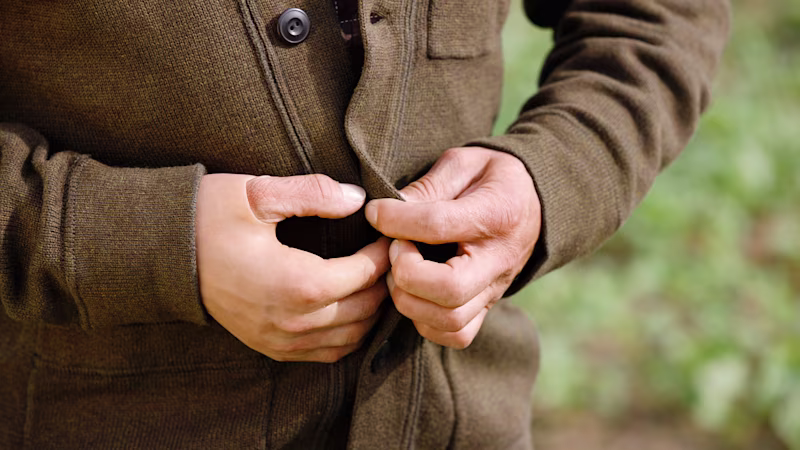 A man buttons his brown jacket using an Ottobock partial hand silicone prosthesis