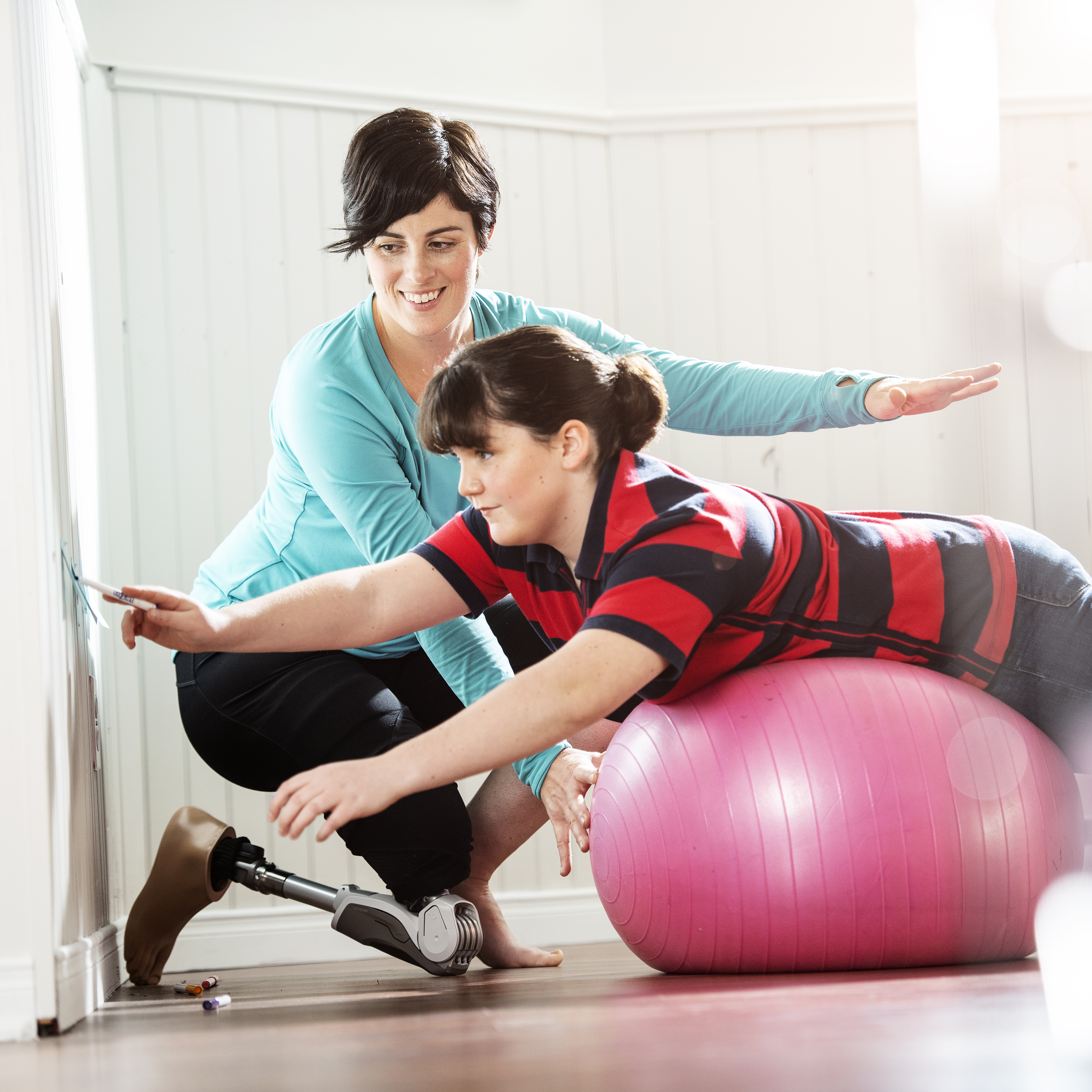 A Dynion user helps another on an exercise ball 